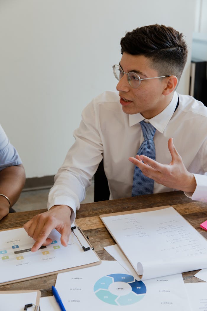 Focused professional discussing strategy during a meeting with graphs and documents.